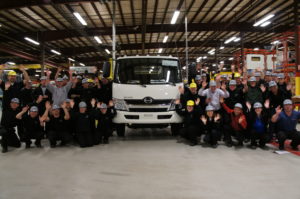employees standing in front of truck in factory