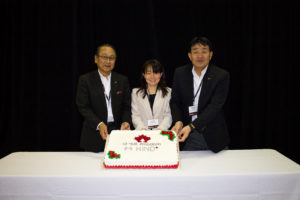 three people holding up a cake