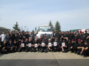 group of people in front of truck hold up number signs