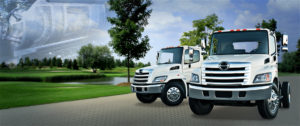 two hino trucks parked near a pond
