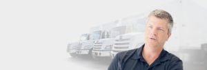 Man speaking while sitting in front of a background of trucks